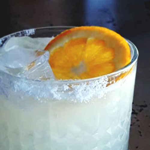 Close up of a classic margarita in a rocks glass featuring the salt rim and citrus garnish.